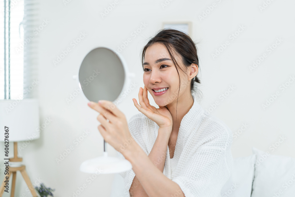 Asian beautiful woman looking at the mirror after apply lotion on face. Asian beautiful woman looking at the mirror after apply lotion on face.