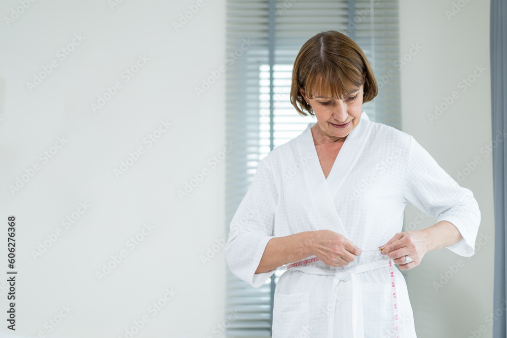Caucasian elderly woman use tape measuring waist in bedroom at home. Caucasian elderly woman use tape measuring waist in bedroom at home.