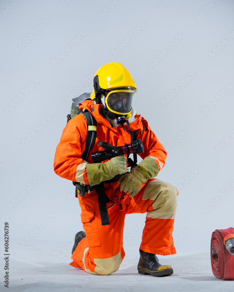 professional firefighter is sitting and kneeling down looking at the fire hose on the floor on a white background. professional firefighter is sitting and kneeling down looking at the fire hose on the floor on a white background.