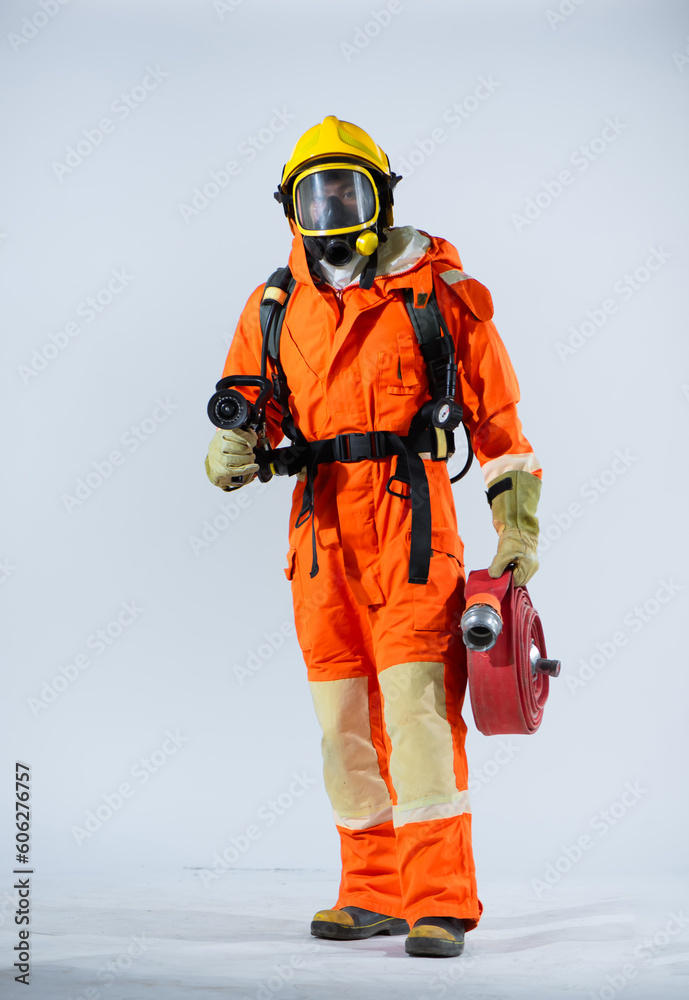 Professional firefighter standing confidently on white background while holding a fire hose. Professional firefighter standing confidently on white background while holding a fire hose.
