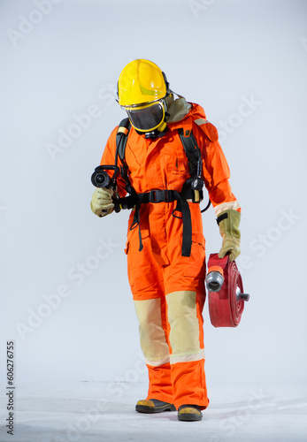 Professional firefighter wearing a yellow helmet standing with head down and holding fire hose on white background. © DSM