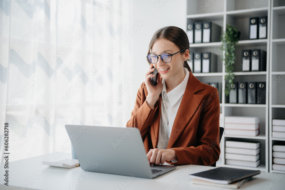 Confident business expert attractive smiling young woman typing laptop ang holding digital tablet on desk in creative office.. Confident business expert attractive smiling young woman typing laptop ang holding digital tablet on desk in creative office..