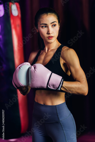 Female Boxer training in Boxing Club. Woman Boxing fighters training at gym. Strong muscular woman practicing box in pink boxing gloves in gym. © kanpisut