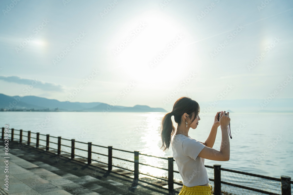 夕暮れの海で写真を撮る女性