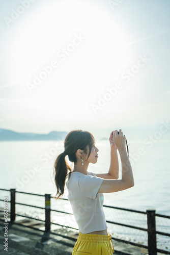 夕暮れの海で写真を撮る女性