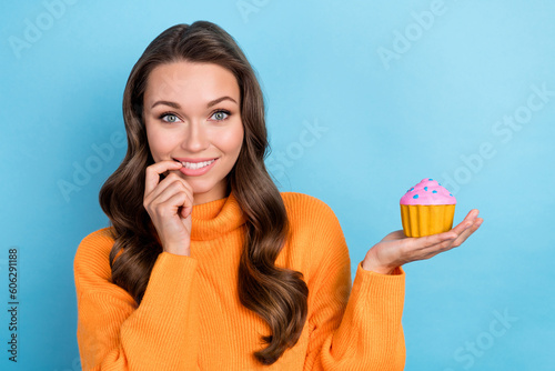 Portrait of positive lady holding yummy fresh biscuit want eating but weight loss isolated on blue color background