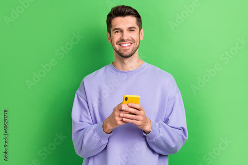 Photo of nice cheerful person beaming smile hold use telephone isolated on green color background