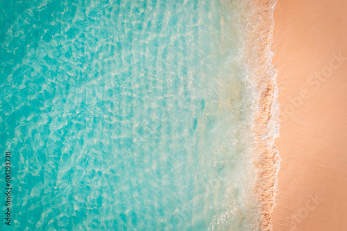 Summer seascape beautiful waves, blue sea water sunset light. Top view from drone. Seaside aerial scene, amazing tropical nature background. Beautiful bright sea waves splashing golden beach sand