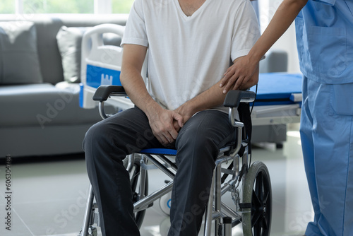 Rehabilitation specialist or physiotherapist giving physical training instruction to a male patient with scrotal pain in a wheelchair at a rehabilitation center health insurance concept.