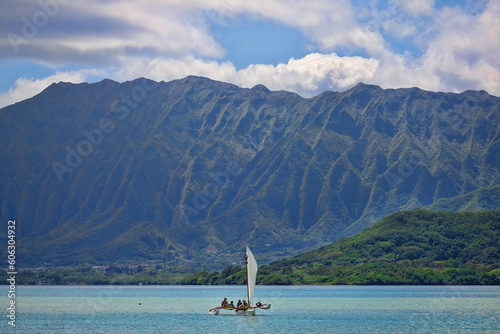 Outrigger canoe sailing in Kaneohe Bay with the Ko'olau mountains the background on the island of Oahu, Hawaii