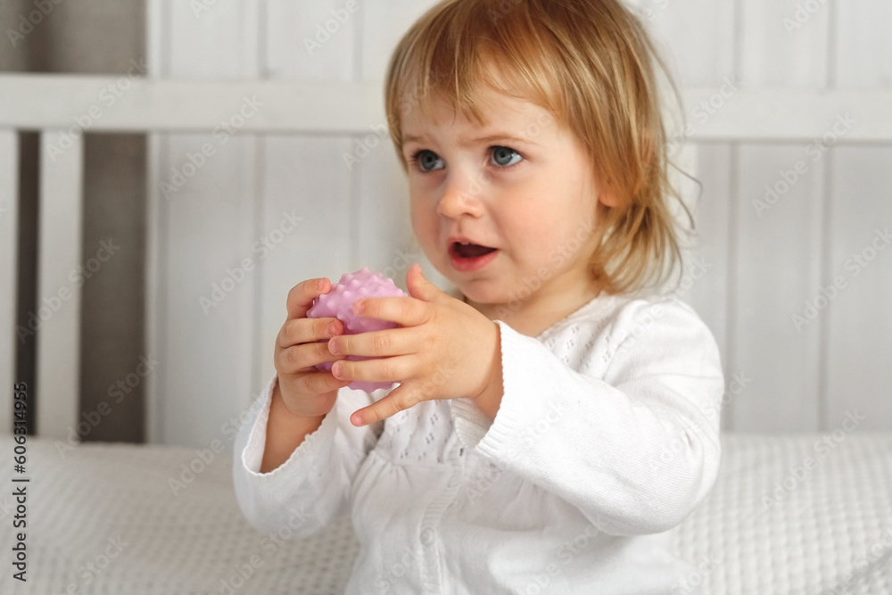 Cute baby girl playing tactile knobby balls. Young child hand plays sensory massage ball. Enhance the cognitive, physical process. Brain development. Support for Children with ADHD, autism, fidgeting Cute baby girl playing tactile knobby balls. Young child hand plays sensory massage ball. Enhance the cognitive, physical process. Brain development. Support for Children with ADHD, autism, fidgeting