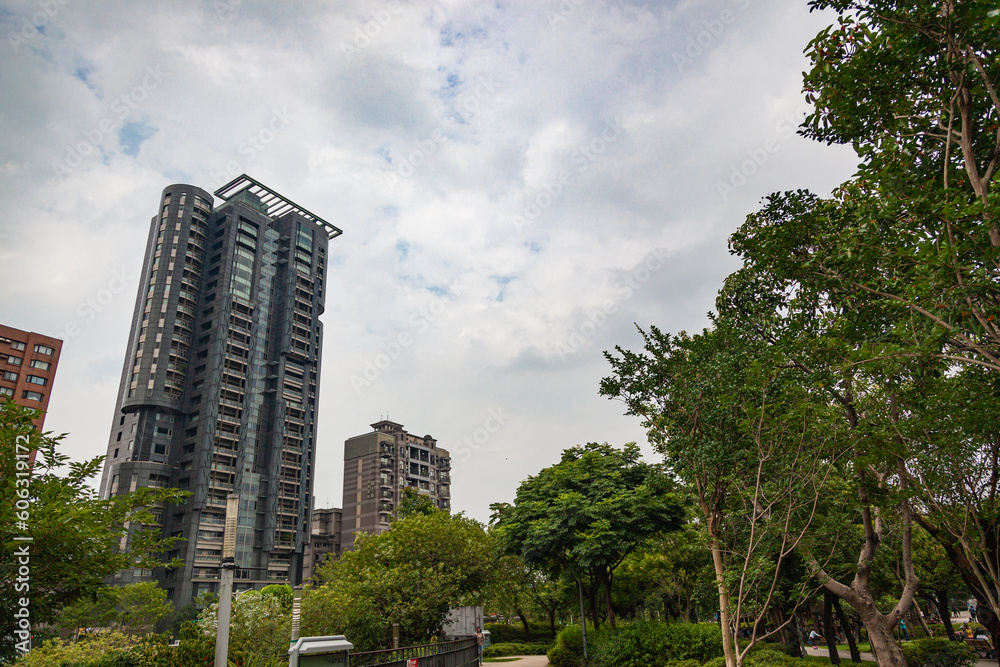 A tall office building under cloudy, blue, and beautiful sky with green trees.