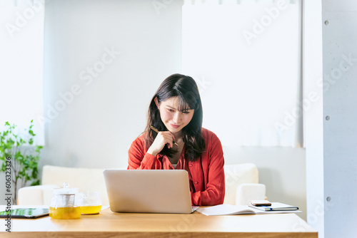 自宅のソファー前のローテーブルのノートパソコンで休日にオンライン講座を受講する30代の1人の女性 photo