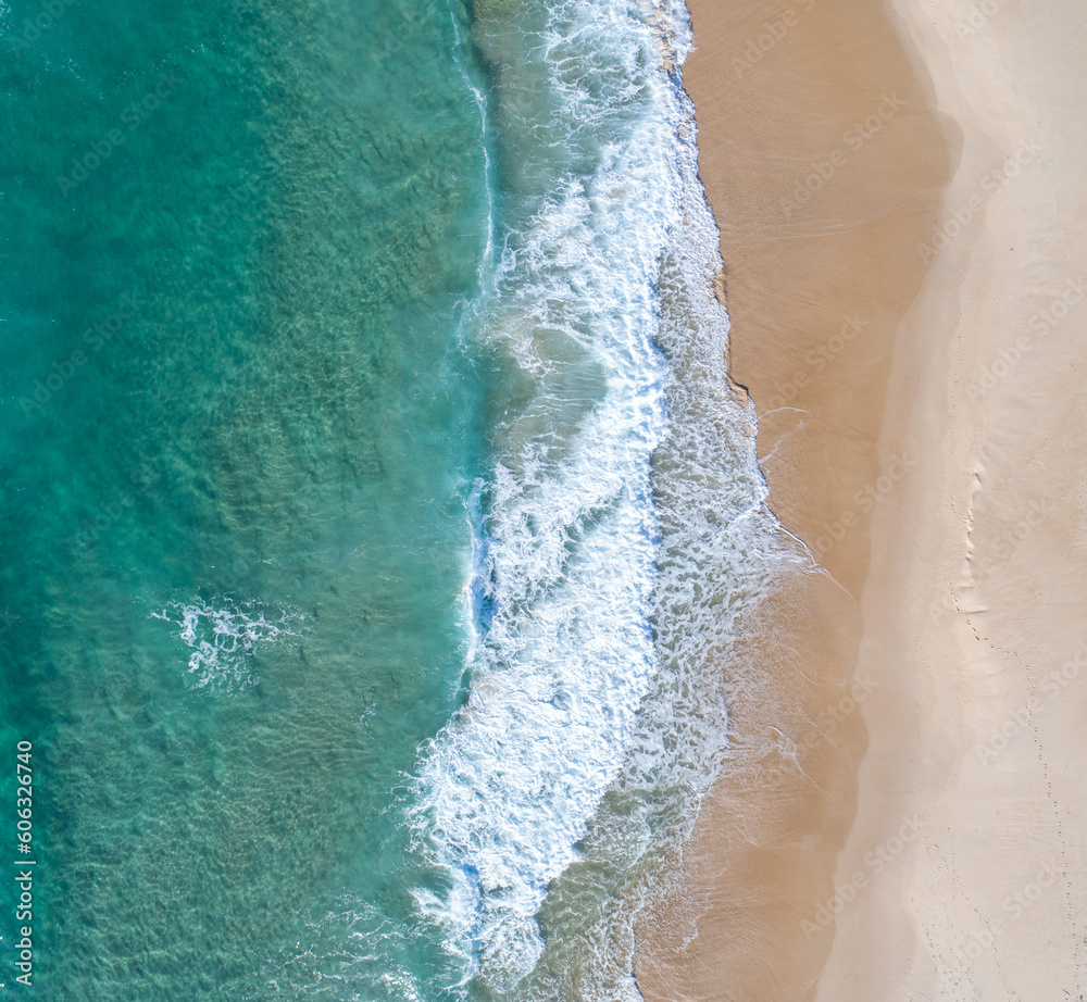 Aerial view of a beach scene with nice waves, blue water and warm sand 
