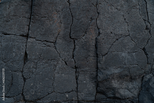 Black volcanic lava bedrock with cracks. Stone background icon.