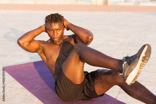 Fitness training outdoors. Handsome African man doing exercises outside. Muscular man training. © JustLife