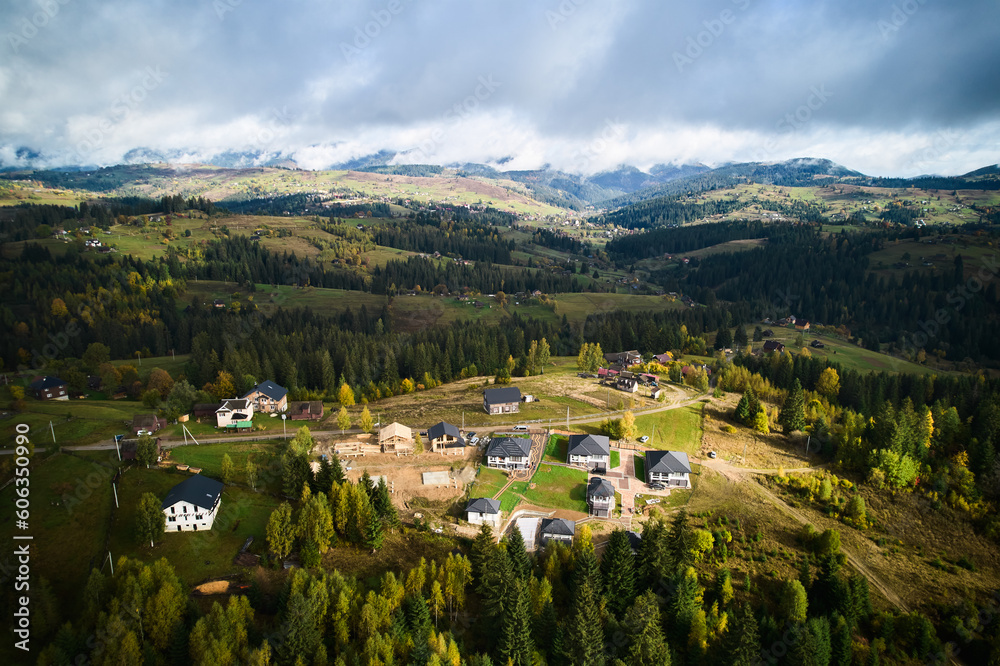 Aerial view of holiday cottages in mountains. Rest houses in coniferous forest. Relaxing far from big city.