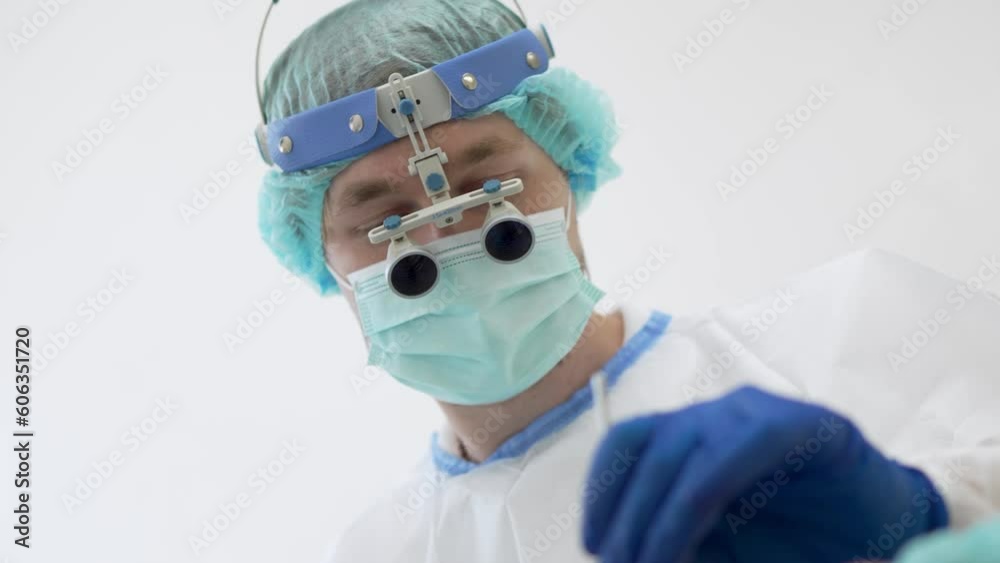 Handheld shot of from below doctor in medical uniform and dental magnifying glasses examining teeth of patient with instrument