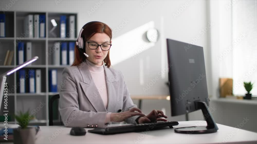young woman call center employee consults client using a headset while sitting at a computer in office young woman call center employee consults client using a headset while sitting at a computer in office