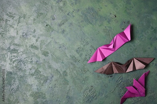 Purple and black paper origami bats on a green concrete background with space for text. DIY concept  children s art  creative. Halloween holiday.
