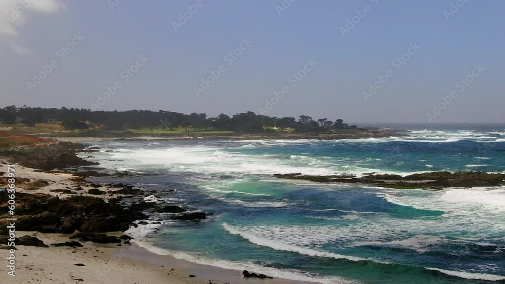Aerial cinematic drone Pebble beach California spring windy waves crashing white sand deep blue aqua Pacific Ocean stunning golf course in background downward movement Aerial cinematic drone Pebble beach California spring windy waves crashing white sand deep blue aqua Pacific Ocean stunning golf course in background downward movement
