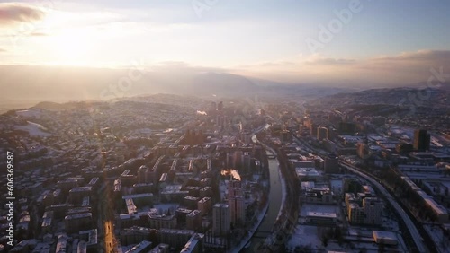 Aerial cinematic drone snowy river roads winter Olympic downtown snowy frozen Sarajevo City town center Bosnia and Herzegovina landscape afternoon sunset golden purple circle right movement photo