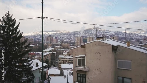 Aerial cinematic drone winter war zone bullet holes on buildings Olympic downtown snowy frozen Sarajevo City town center Bosnia and Herzegovina frozen landscape sunset slow upward movement photo