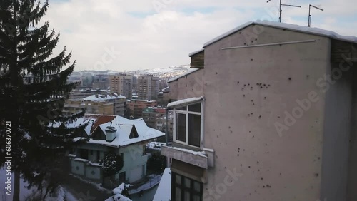 Aerial cinematic drone winter war zone bullet holes on buildings Olympic downtown snowy frozen Sarajevo City town center Bosnia and Herzegovina frozen landscape sunset slow left movement photo