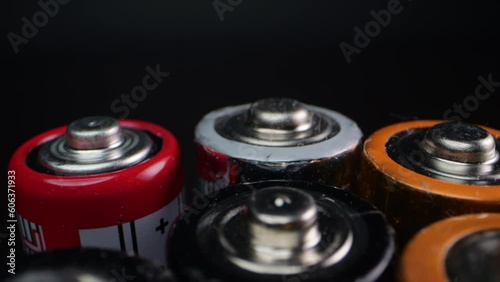 Camera zooms in on used alkaline batteries, commonly used in electronic devices. Filmed in macro on a dark surface. photo