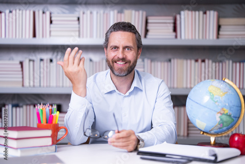 Portrait of teacher in library classroom. Handsome teacher in university library. Teachers Day. Teacher giving classes. School teacher in library. Tutor in classroom at college library.