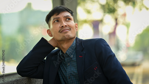 Wallpaper Mural Young businessman in formalwear sitting on bench in urban park and looking thoughtfully Torontodigital.ca