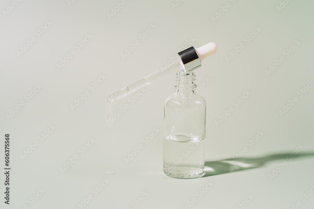 Glass bottle with serum with a pipette on a green background. Glass bottle with serum with a pipette on a green background.