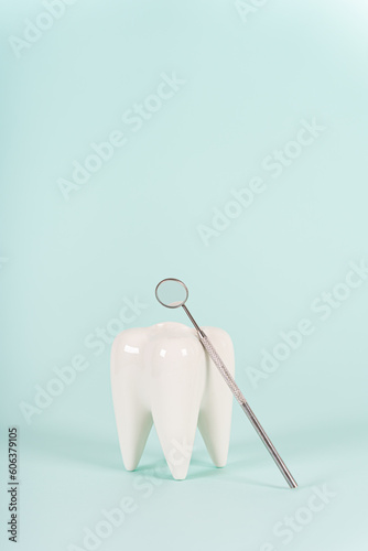 Healthy white tooth model and dentist mirror on blue background. Copy space. Teeth care  whitening  dental treatment  tooth extraction  implant concept. Dental clinic special offer. Vertical