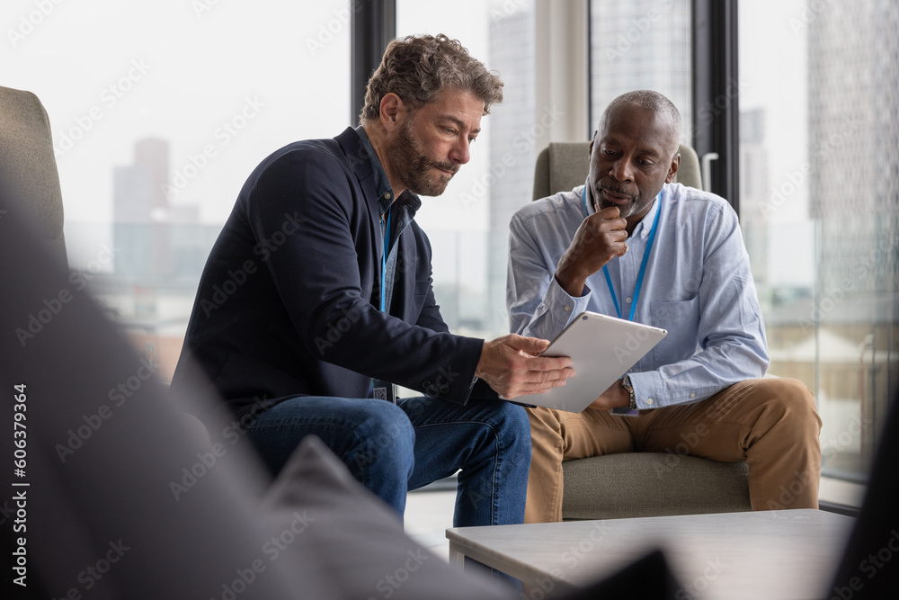 Two senior business executives in a meeting looking at a digital tablet Two senior business executives in a meeting looking at a digital tablet