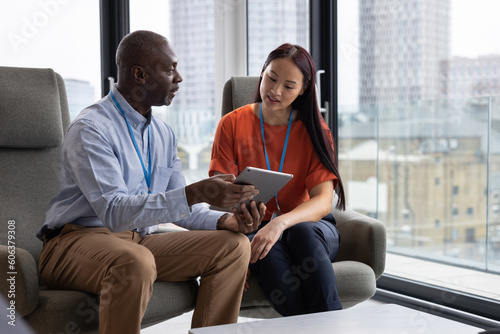 Young businesswoman being mentored by senior businessman in a modern office with view of city photo