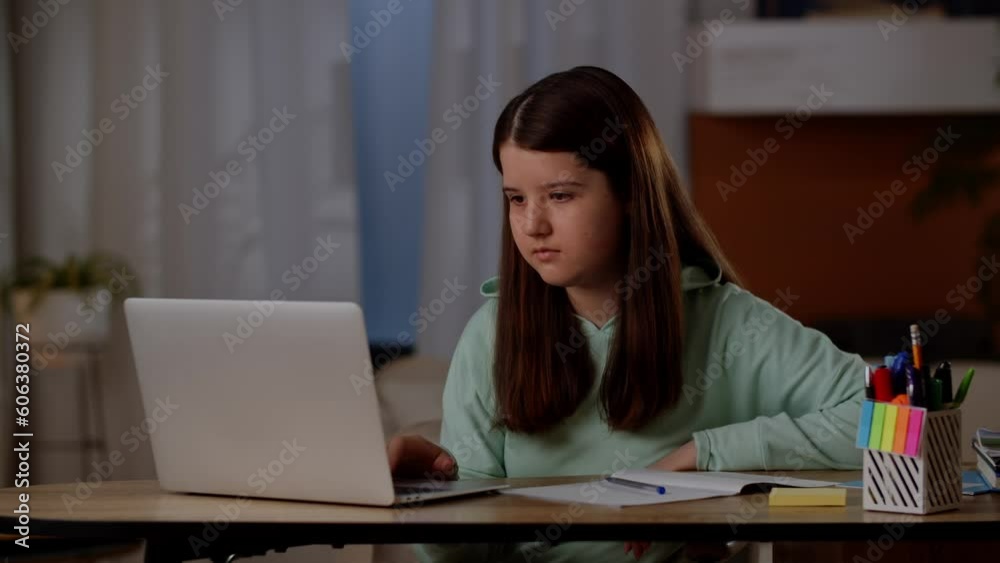 A brunette girl sits at a table and surfs the Internet on her laptop. The girl uses the Internet on the computer to do homework. A brunette girl sits at a table and surfs the Internet on her laptop. The girl uses the Internet on the computer to do homework.