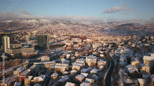 Aerial cinematic drone cars driving snowy roads winter Olympic downtown snowy frozen Sarajevo City town center Bosnia and Herzegovina frozen landscape afternoon sunset golden pan up forward movement photo
