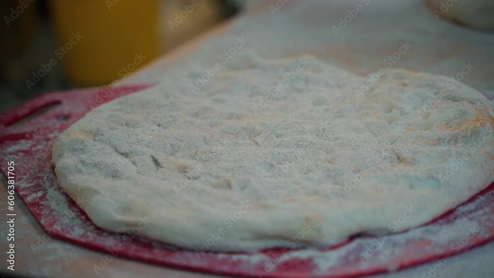 baker forms flat dough with his hands and stands flour over it baker forms flat dough with his hands and stands flour over it