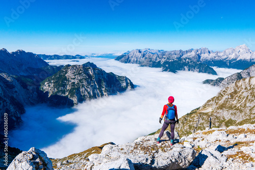 Young woman with backpack on the mountain peak and mountain canyon at sunny day. Summer in Triglav national park, Slovenia. Colorful landscape with girl on path. Trekking and hiking