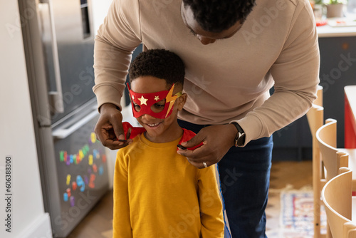 Father putting superhero cape on son