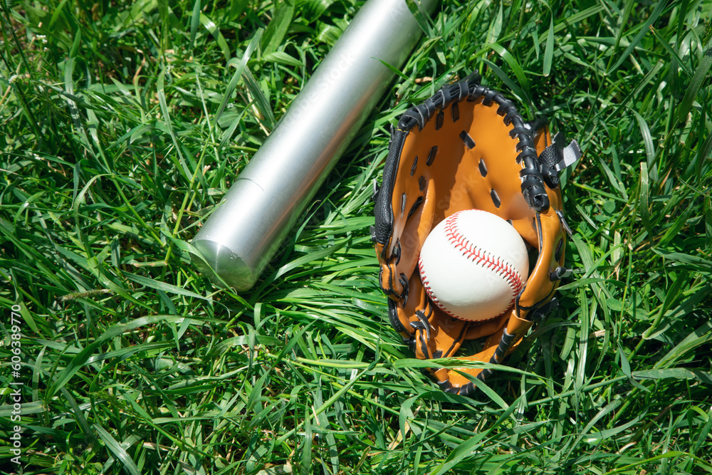 Naklejka premium Baseball bat and baseball on the green grass background.
