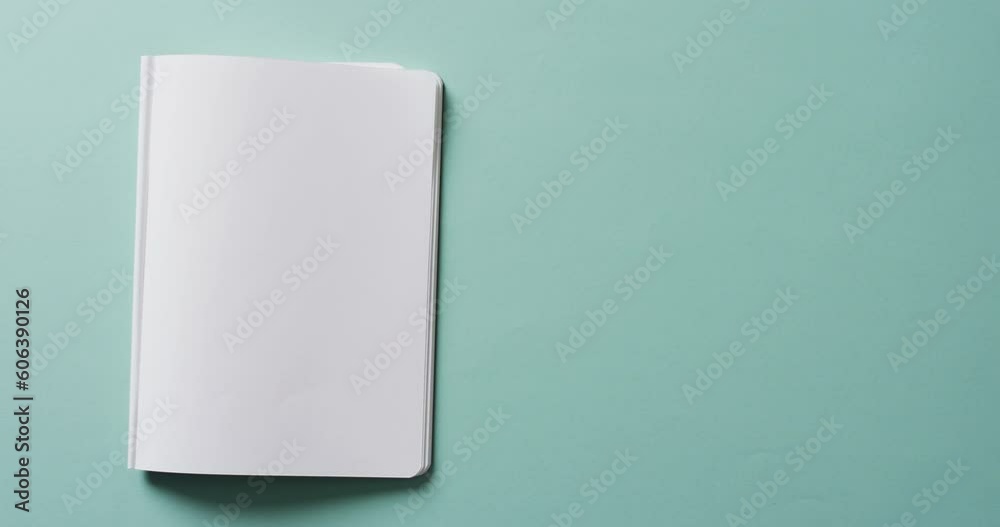 Close up of open blank book with copy space on green background in slow motion Close up of open blank book with copy space on green background in slow motion