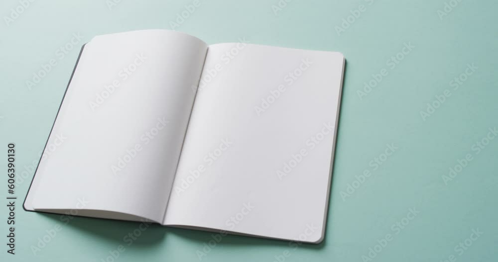 Close up of open blank book with copy space on green background in slow motion