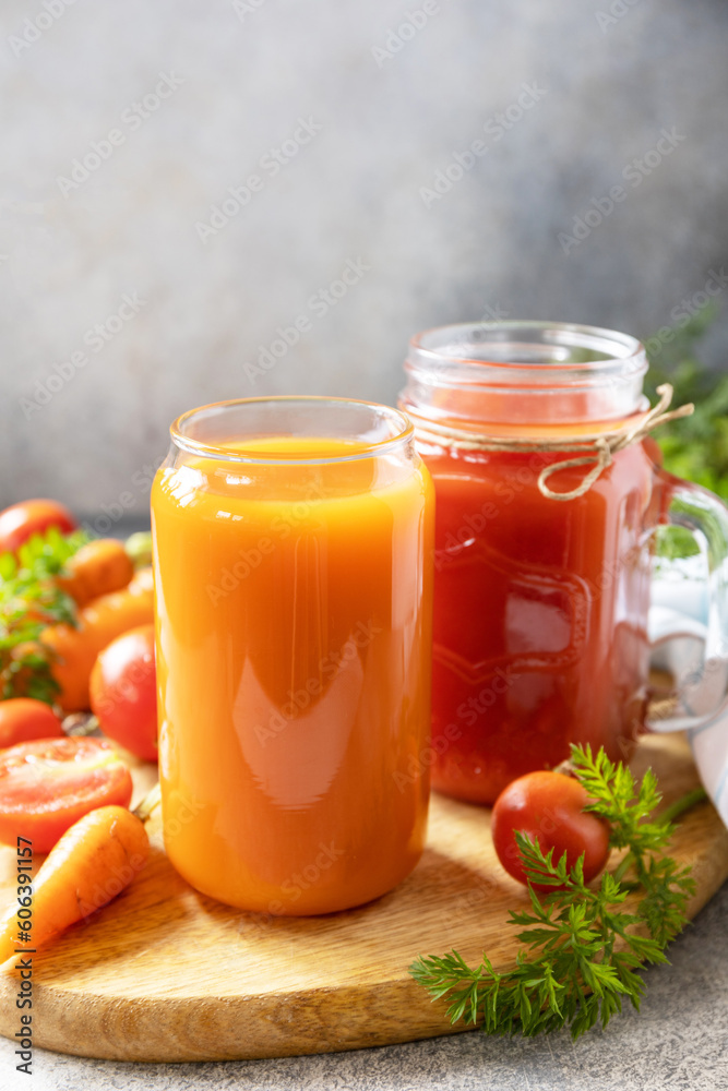 Tomato and carrot juice in a glasses on a stone table. Vitamins drinks juice carrot and tomato. Healthy lifestyle. Copy space. Tomato and carrot juice in a glasses on a stone table. Vitamins drinks juice carrot and tomato. Healthy lifestyle. Copy space.