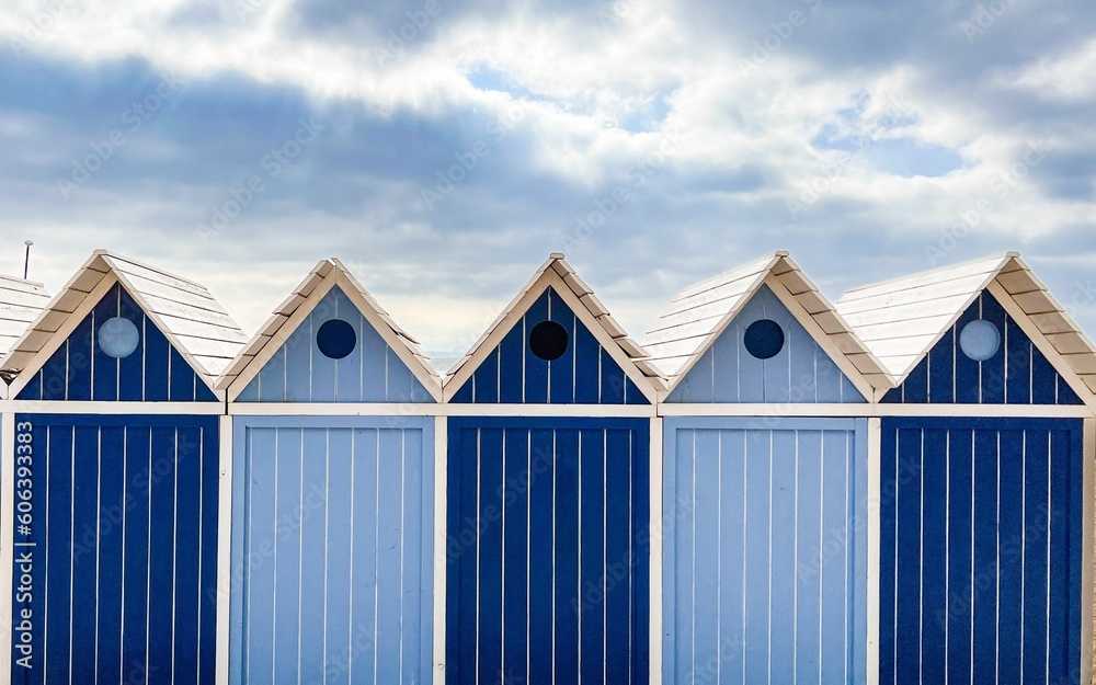 Facade of a row of blue cabins by the sea