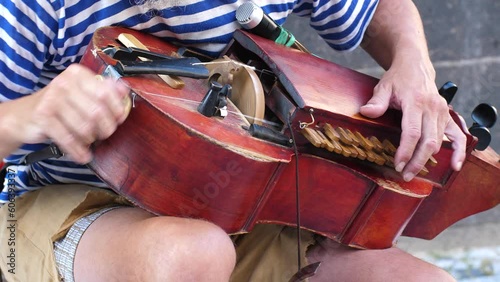 street musician playing retro hurdy gurdy or wheel-fiddle vintage music hand-crank acoustic string instrument, authentic traditional street music player. photo