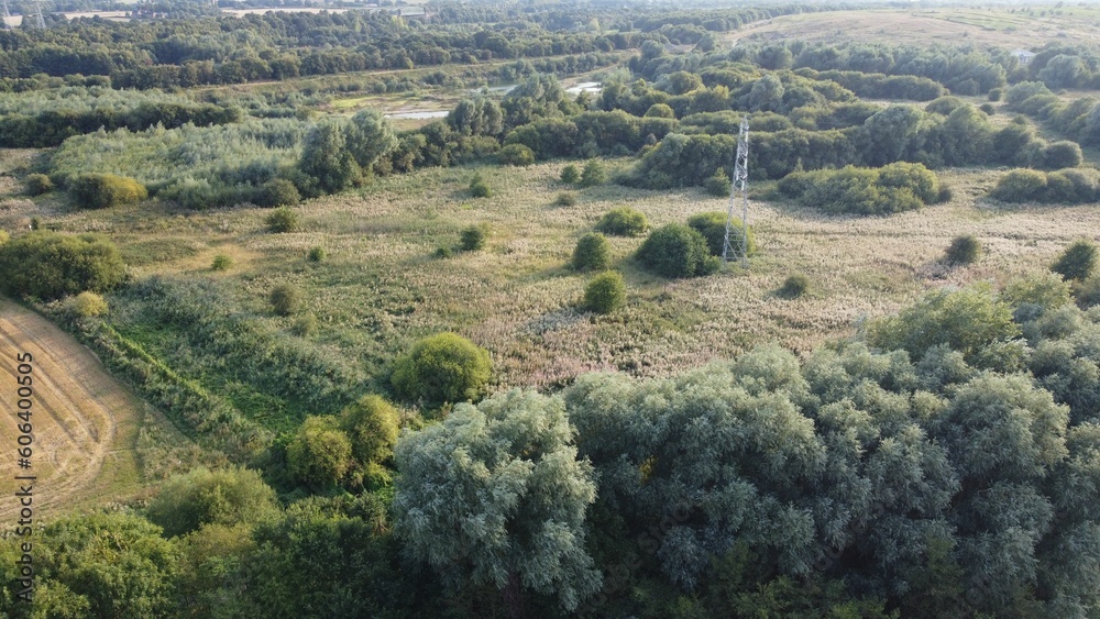 Aerial shot of an electricity pylon in a field during the day