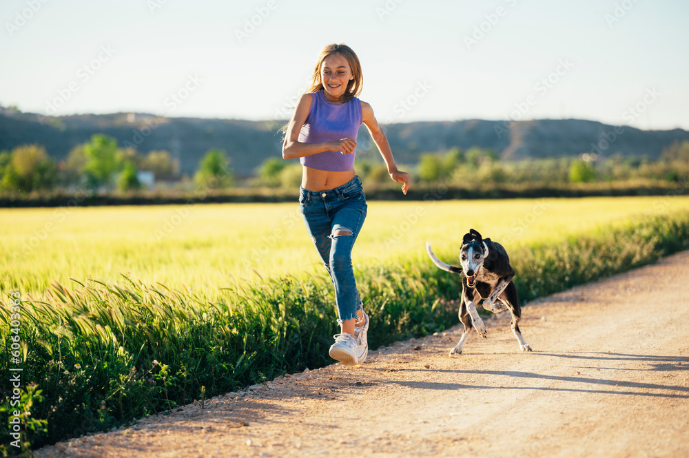 Φωτογραφία Beautiful young blonde woman running in the field with her greyhound dog