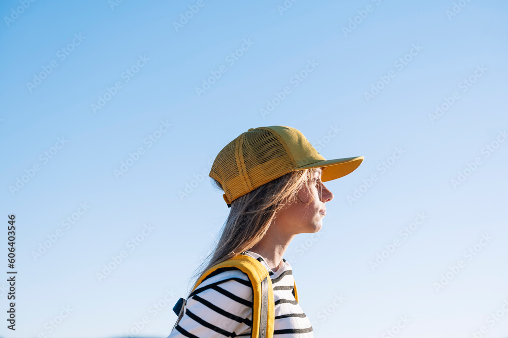 Outdoor portrait of a beautiful young blonde woman in a yellow cap and a bracket on her teeth.