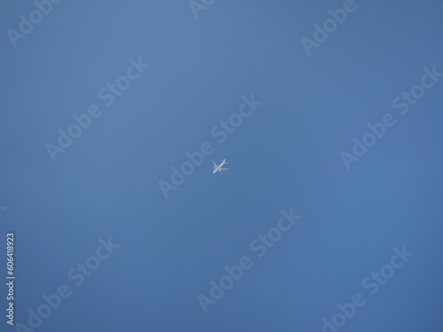 Scenic view of an airplane flying in the blue sky background in daylight